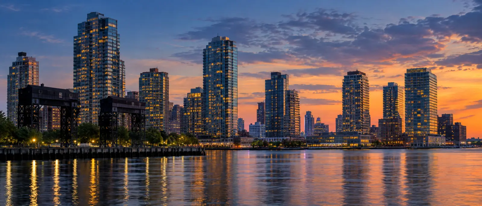 The Long Island City, Queens waterfront at dusk, lit towers reflected in the East River